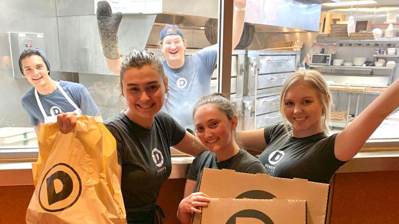 a group of dewey's employees smile and wave