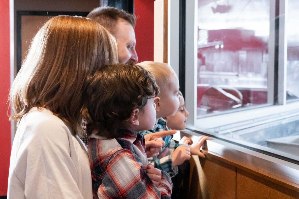 a family huddles together to watch their pizza being made