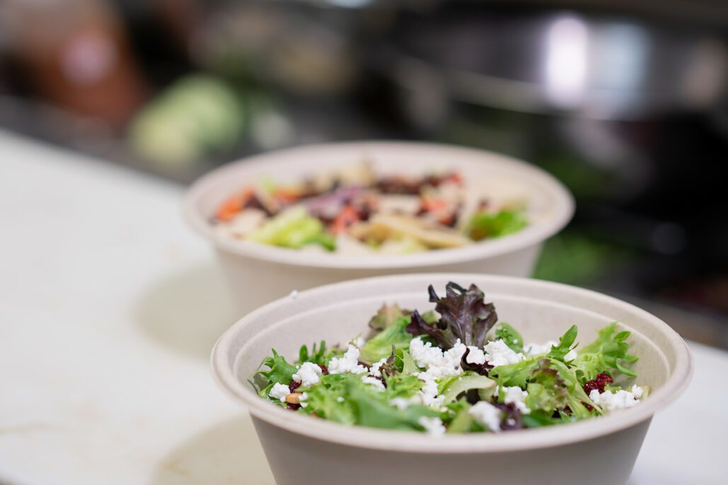 two salads sitting in bowls on a table