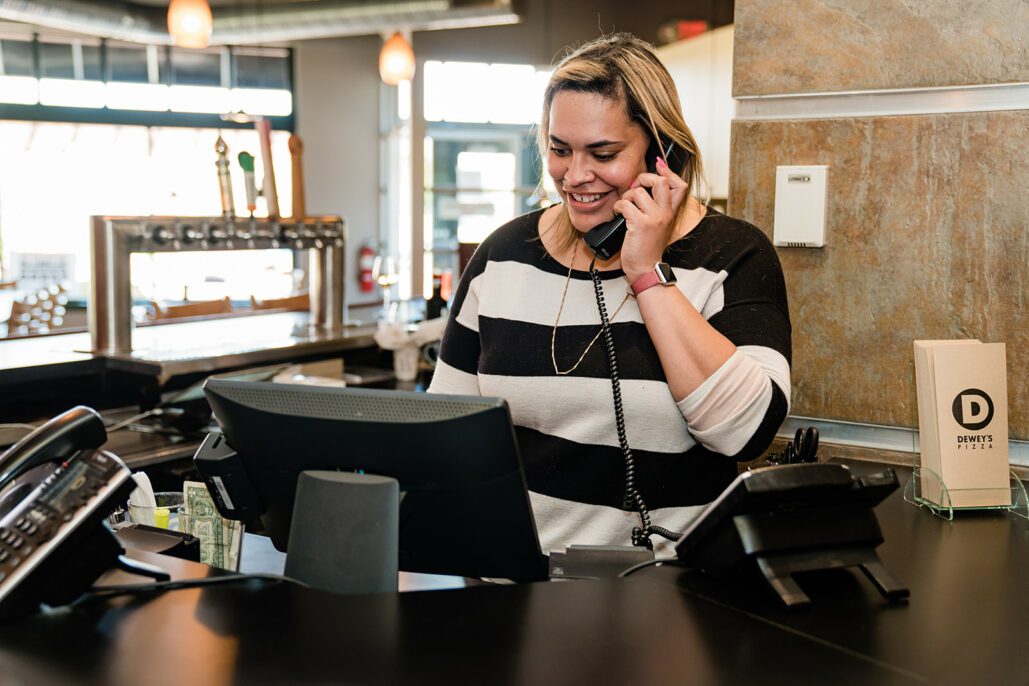 a woman smiles while answering the phone